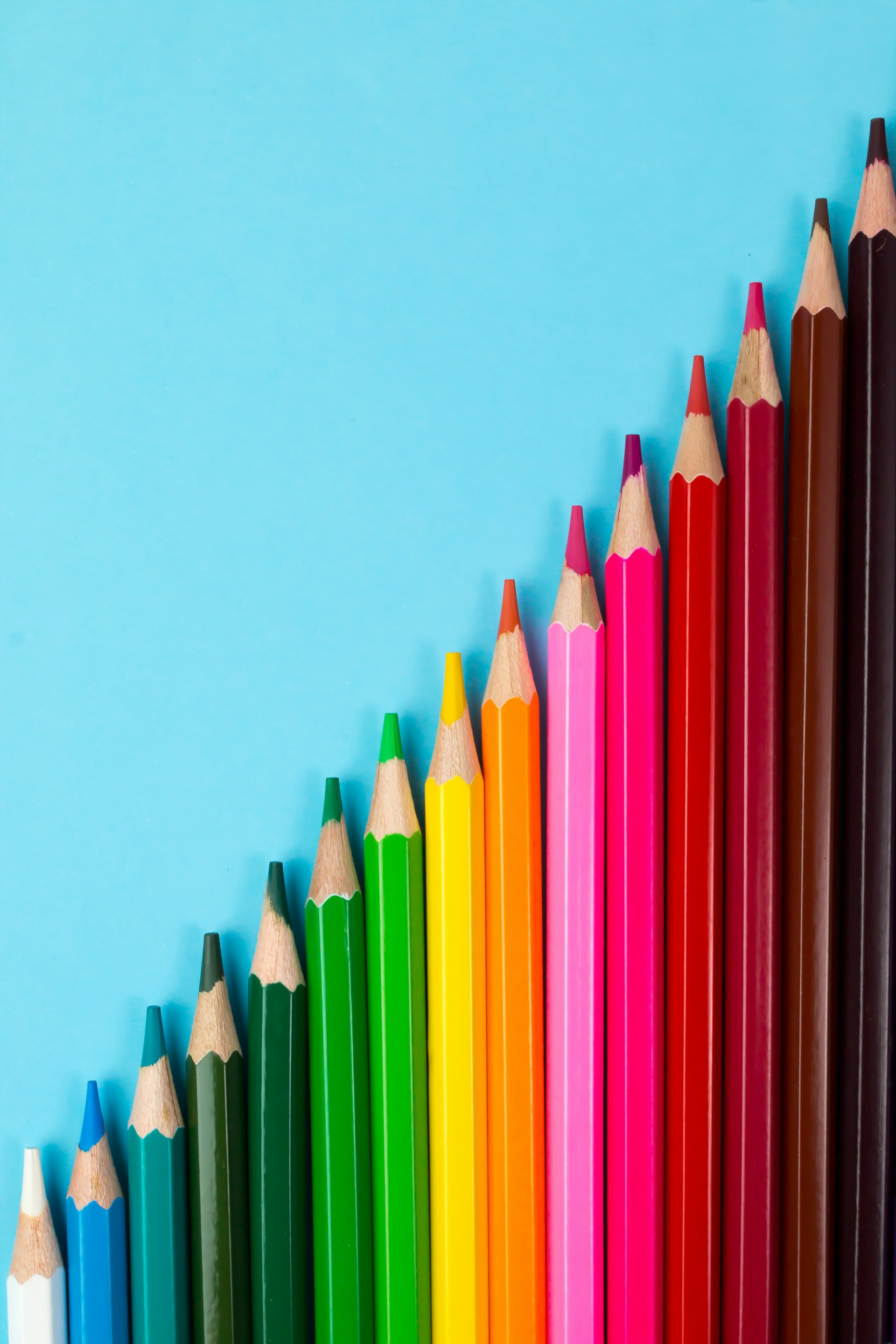 A vibrant array of colored pencils neatly aligned in a straight line, showcasing a spectrum of hues.